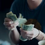 focus photography of person counting dollar banknotes